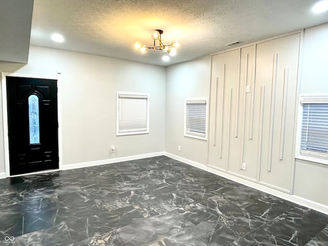 entryway with a chandelier and a textured ceiling