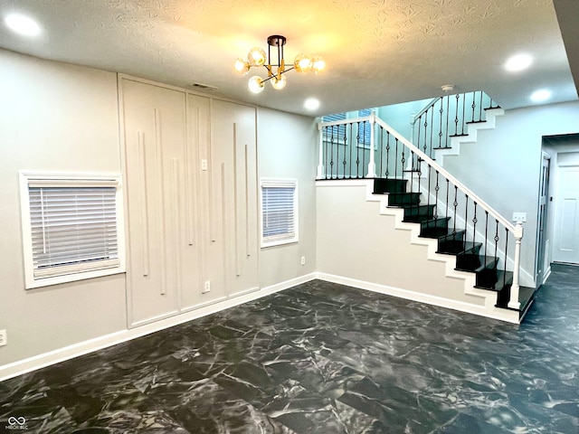 stairway featuring an inviting chandelier and a textured ceiling