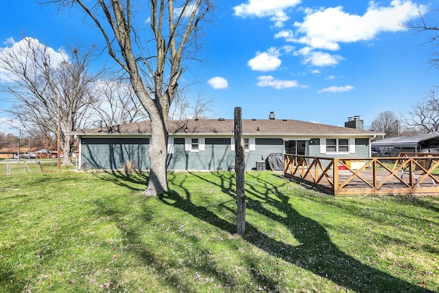 rear view of property featuring a wooden deck and a lawn