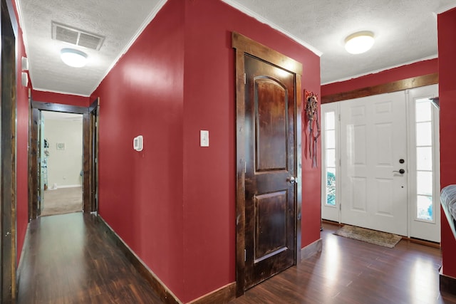 foyer entrance featuring a textured ceiling and dark carpet