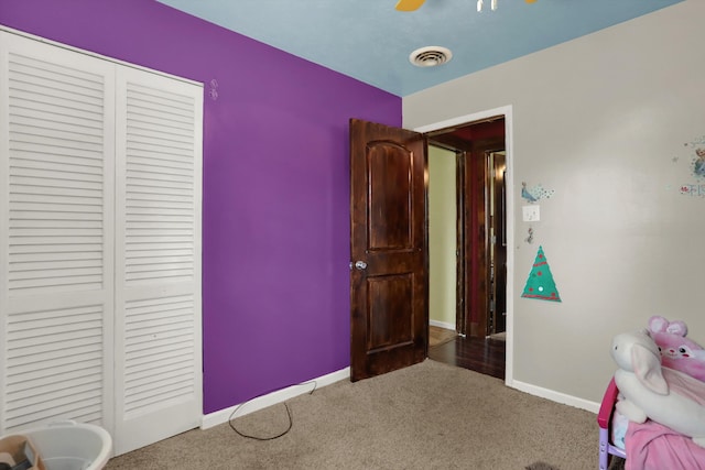 unfurnished bedroom with a closet, dark colored carpet, and ceiling fan