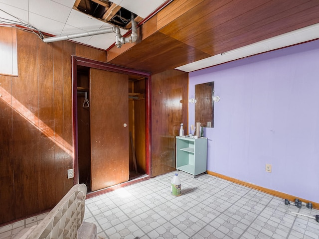 basement featuring wood walls and tile floors