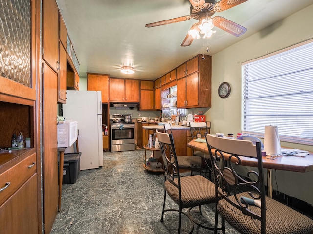 kitchen with ceiling fan, stainless steel range oven, white refrigerator, and dark tile flooring