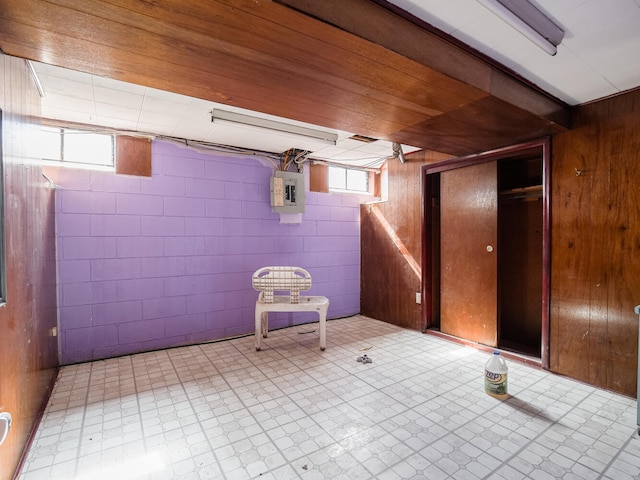 basement with wood walls and light tile floors