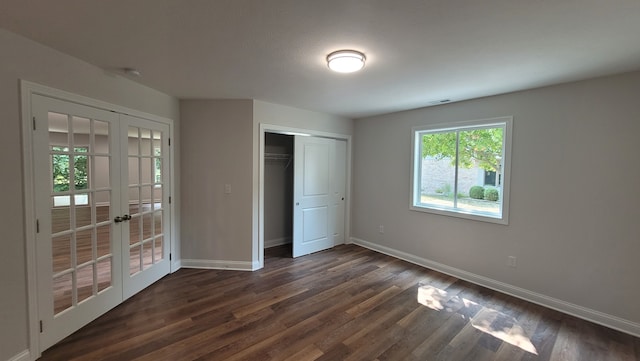 unfurnished bedroom with dark hardwood / wood-style flooring, a closet, and french doors