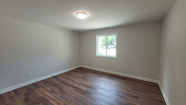 empty room featuring dark hardwood / wood-style flooring and a textured ceiling