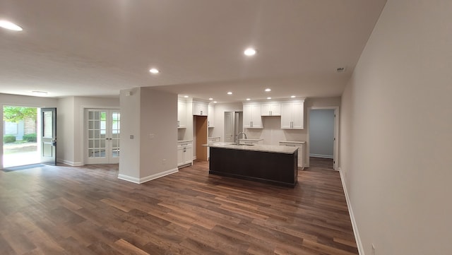 kitchen with sink, french doors, white cabinetry, dark hardwood / wood-style floors, and a center island with sink