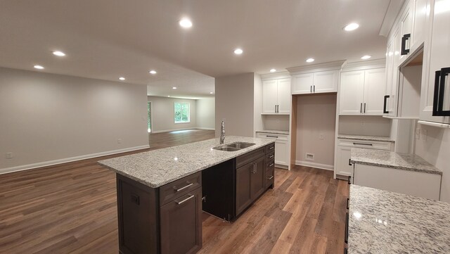 kitchen featuring dark wood-type flooring, sink, dark brown cabinetry, and a kitchen island with sink