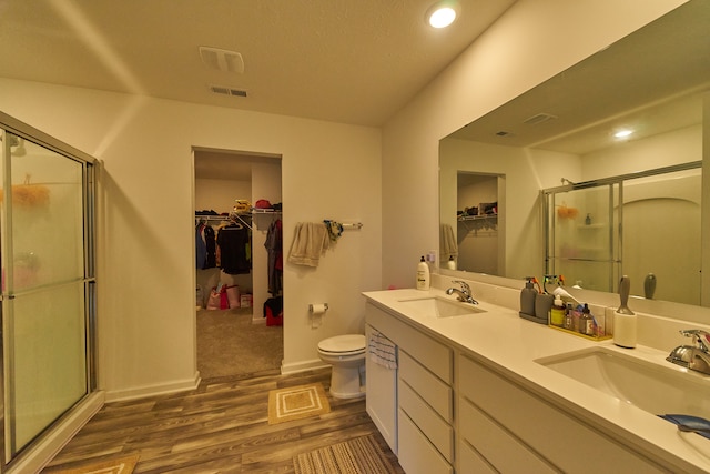 bathroom featuring an enclosed shower, hardwood / wood-style floors, toilet, and dual bowl vanity