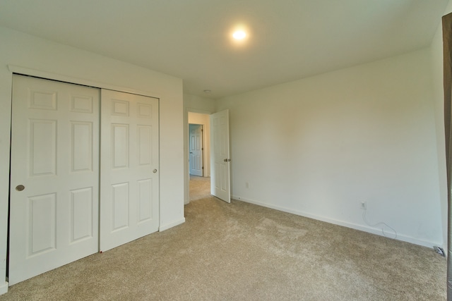 unfurnished bedroom with light colored carpet and a closet