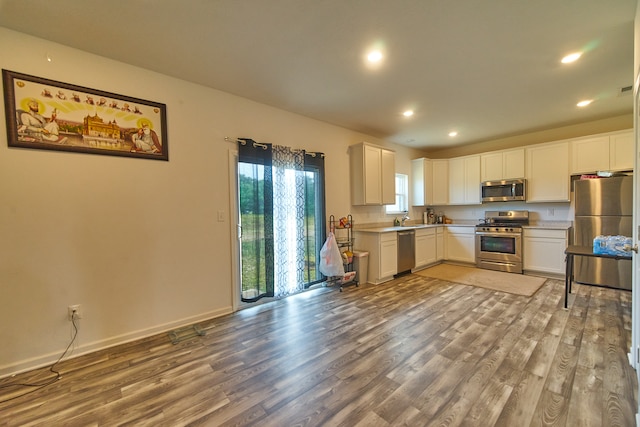 kitchen with white cabinets, appliances with stainless steel finishes, hardwood / wood-style floors, and sink