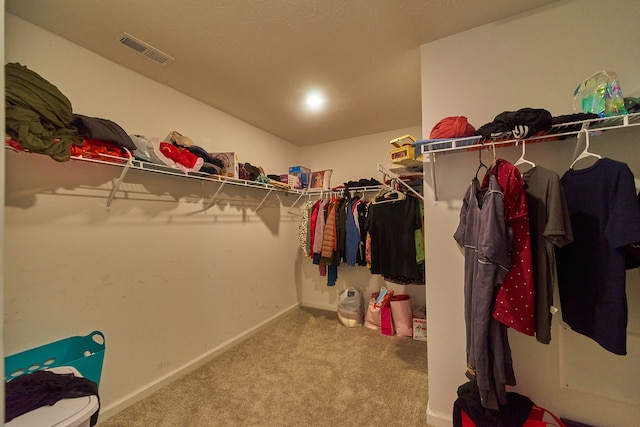 walk in closet featuring light colored carpet