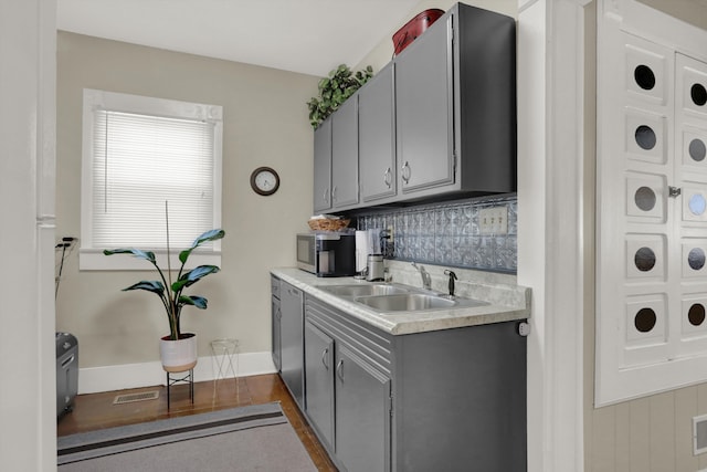 kitchen with sink, gray cabinetry, appliances with stainless steel finishes, dark wood-type flooring, and tasteful backsplash