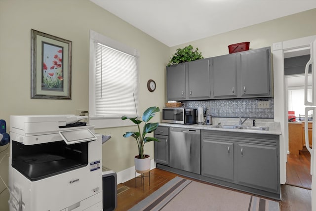 kitchen featuring hardwood / wood-style floors, gray cabinetry, backsplash, sink, and stainless steel appliances