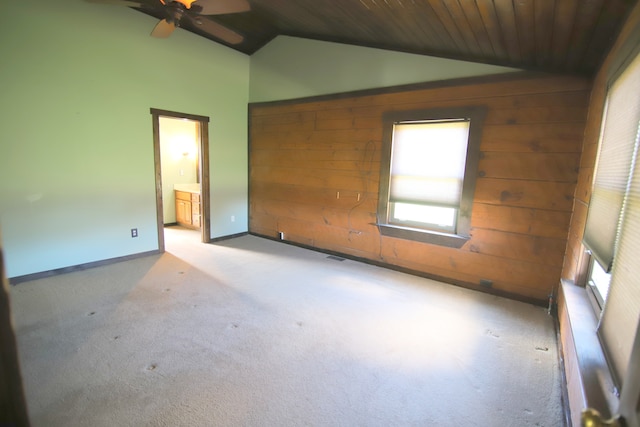 carpeted empty room featuring vaulted ceiling, wood ceiling, wooden walls, and ceiling fan