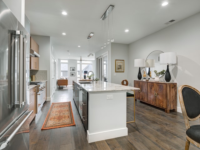 kitchen with decorative light fixtures, dark wood-type flooring, a kitchen island with sink, sink, and high end appliances