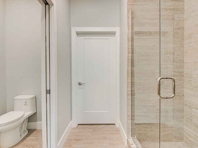 bathroom with a shower with door and toilet