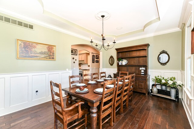 dining room with a raised ceiling, ornamental molding, dark hardwood / wood-style floors, and an inviting chandelier