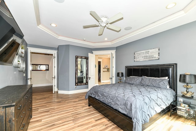 bedroom featuring a tray ceiling, ceiling fan, light hardwood / wood-style flooring, and crown molding