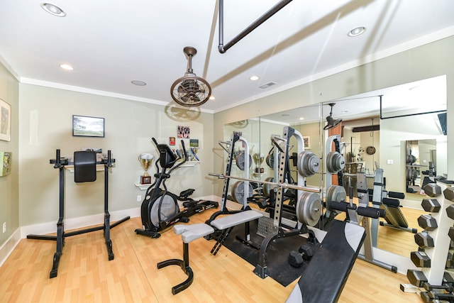 exercise room featuring crown molding and light wood-type flooring