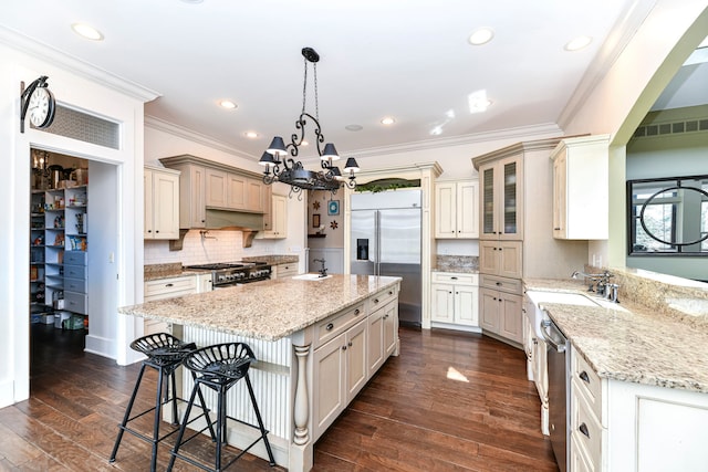 kitchen with premium appliances, a kitchen island, dark wood-type flooring, hanging light fixtures, and an inviting chandelier