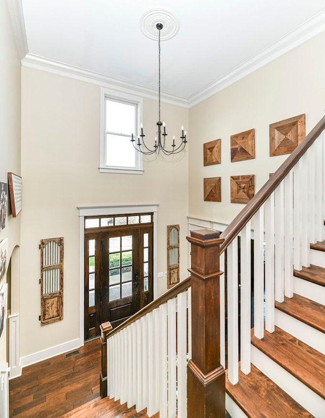 foyer featuring dark hardwood / wood-style flooring, ornamental molding, and a chandelier