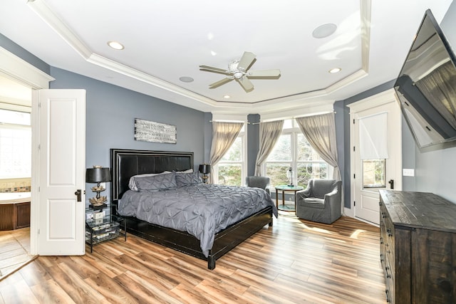 bedroom featuring ceiling fan, light wood-type flooring, and a tray ceiling