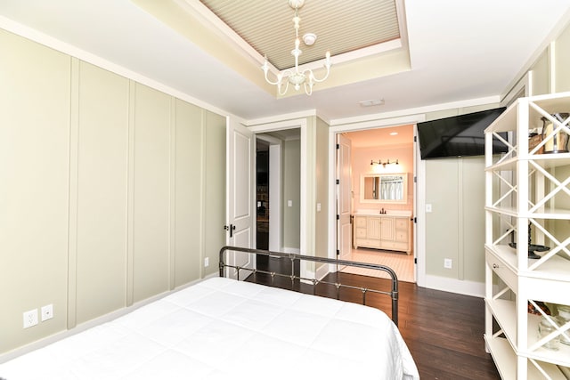 bedroom featuring a chandelier, a tray ceiling, ensuite bath, and wood-type flooring