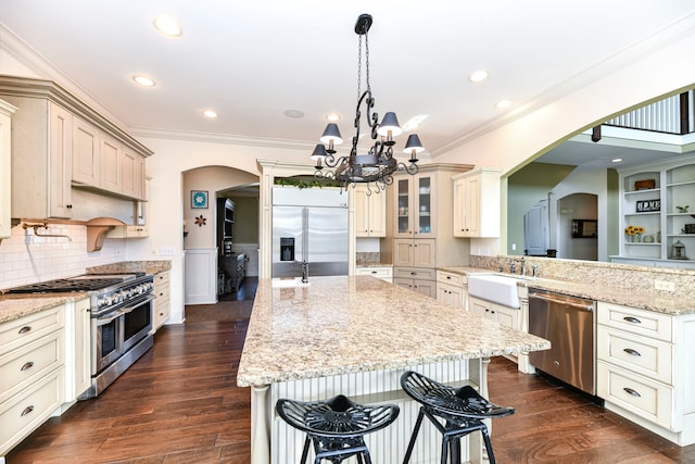 kitchen featuring dark wood-type flooring, high quality appliances, a kitchen bar, a notable chandelier, and light stone countertops