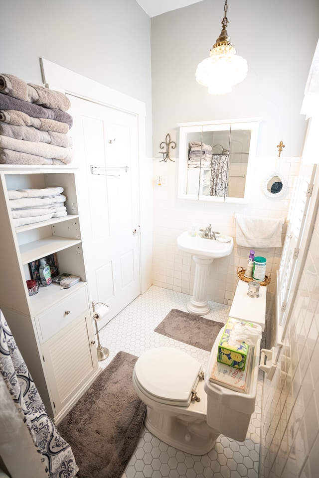 bathroom with tile walls, toilet, tile floors, and sink