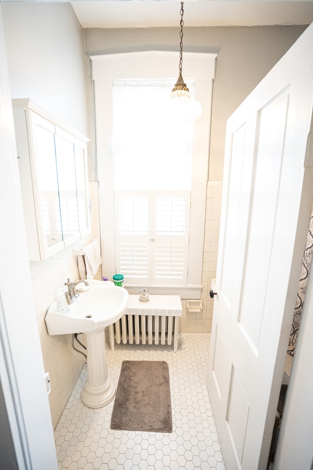 bathroom with a notable chandelier, tile flooring, and tile walls