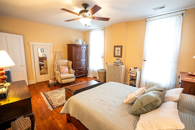 bedroom featuring multiple windows, dark hardwood / wood-style floors, and ceiling fan