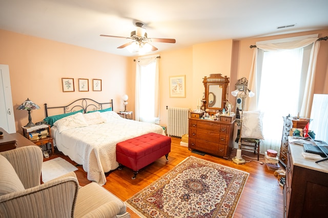 bedroom with ceiling fan, radiator, and wood-type flooring