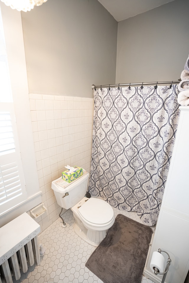 bathroom featuring tile flooring, tile walls, and toilet