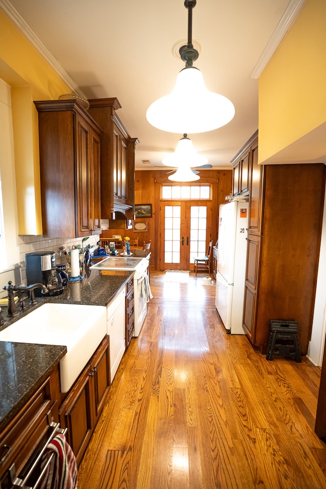 kitchen featuring hanging light fixtures, white appliances, light hardwood / wood-style floors, crown molding, and french doors