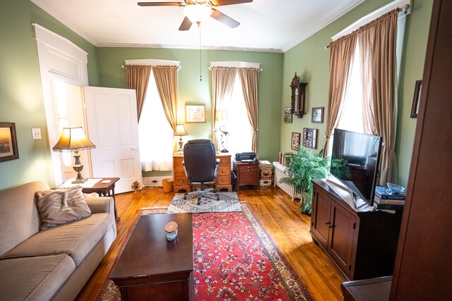 living room featuring crown molding, wood-type flooring, and ceiling fan