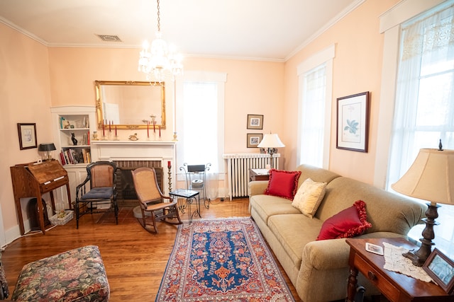 living room with a notable chandelier, plenty of natural light, a brick fireplace, and dark wood-type flooring