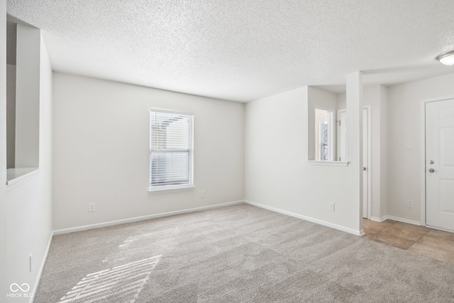 carpeted empty room with a textured ceiling