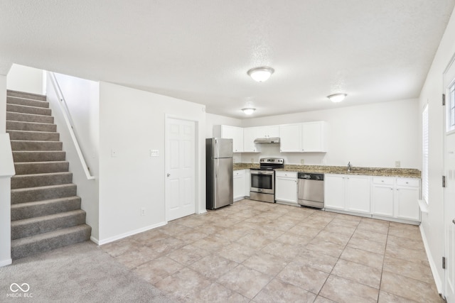 kitchen with light stone countertops, stainless steel appliances, white cabinets, and a textured ceiling