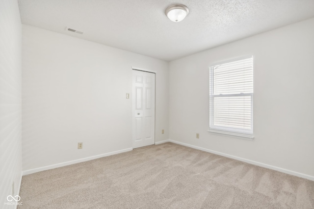 carpeted spare room featuring a textured ceiling