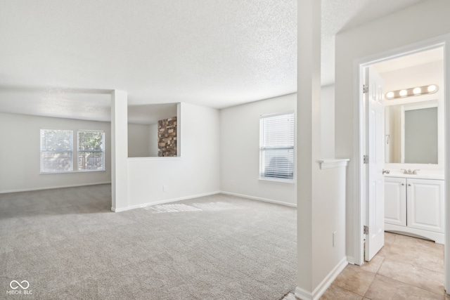 carpeted empty room with a textured ceiling and sink