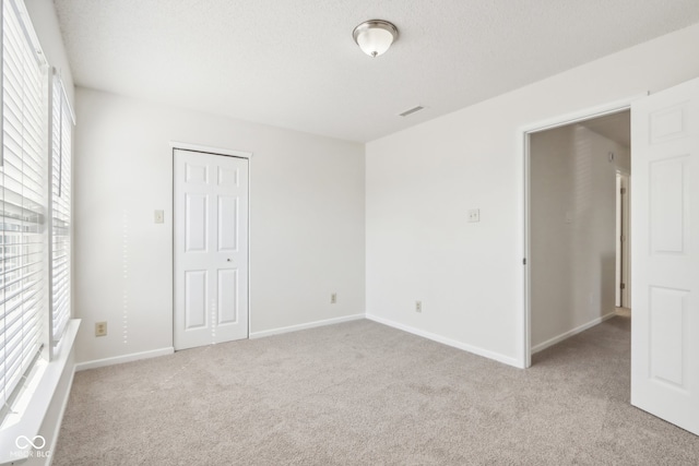 unfurnished bedroom featuring a closet, multiple windows, and light colored carpet