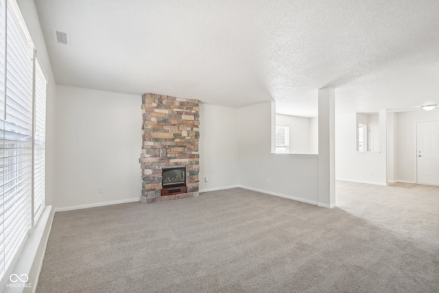 unfurnished living room featuring light carpet, a wealth of natural light, a textured ceiling, and a fireplace