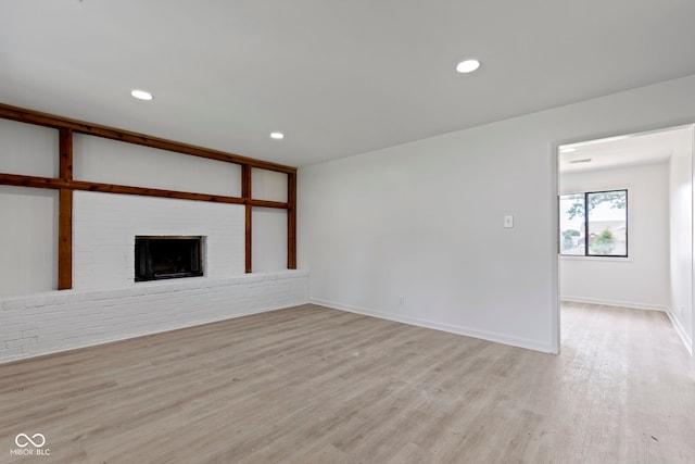 unfurnished living room featuring a brick fireplace and light hardwood / wood-style floors