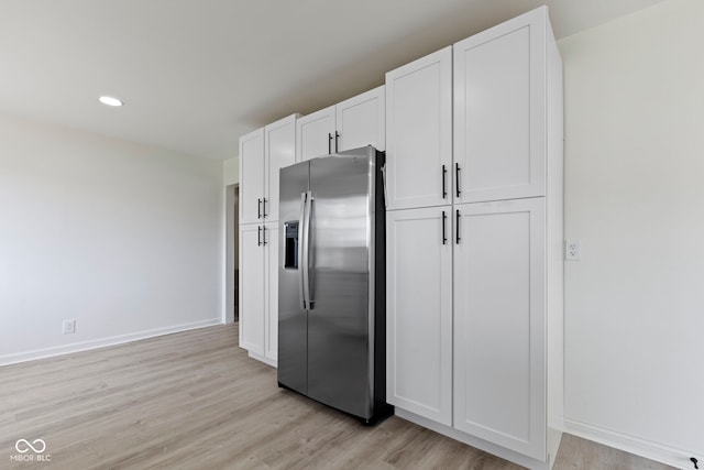 kitchen with stainless steel fridge, light hardwood / wood-style floors, and white cabinets