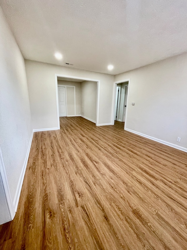 unfurnished room featuring a textured ceiling and light hardwood / wood-style flooring