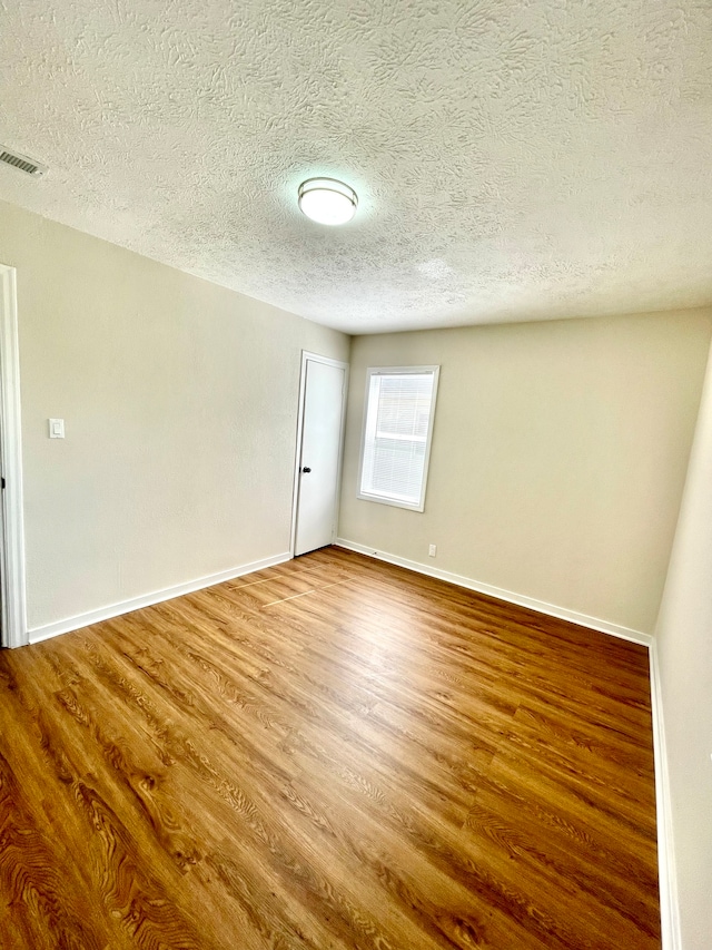 empty room featuring a textured ceiling and hardwood / wood-style floors