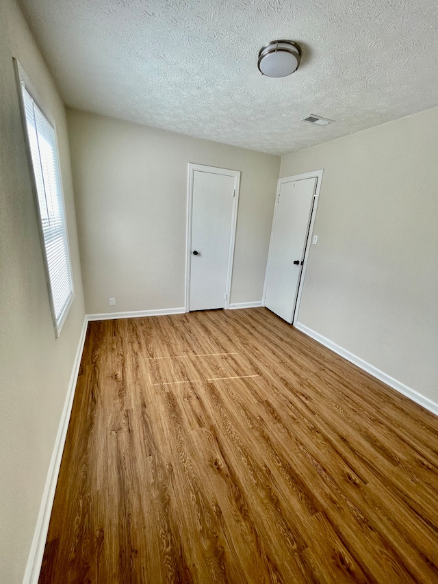 spare room featuring plenty of natural light, a textured ceiling, and light wood-type flooring