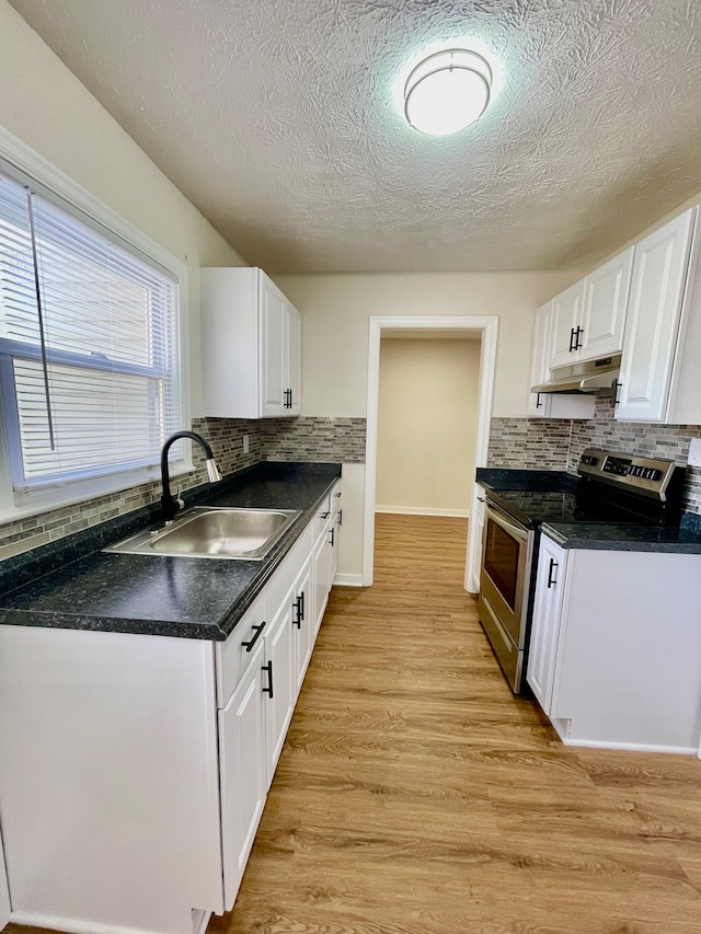 kitchen with tasteful backsplash, stainless steel range with electric cooktop, light hardwood / wood-style floors, sink, and white cabinetry