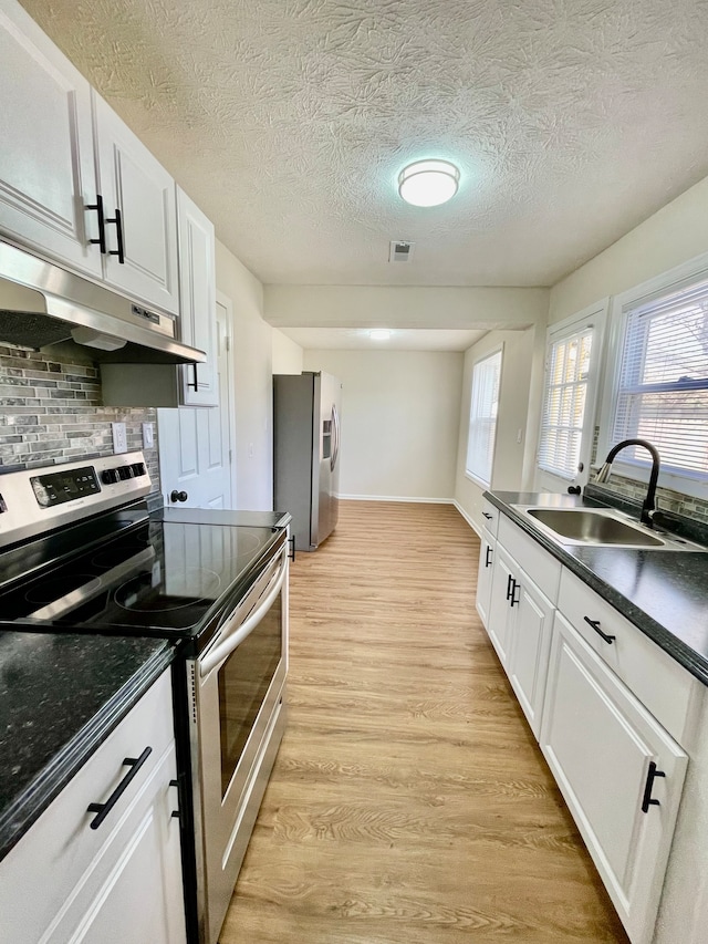 kitchen with white cabinetry, backsplash, appliances with stainless steel finishes, sink, and light wood-type flooring